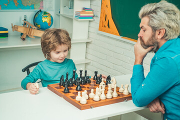 Fathers day. Concentrated boy developing chess strategy. Clever concentrated and thinking child while playing chess.