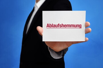 Ablaufshemmung. Anwalt (Mann) mit Karte in der Hand. Text/Wort auf Schild. Hintergrund blau.