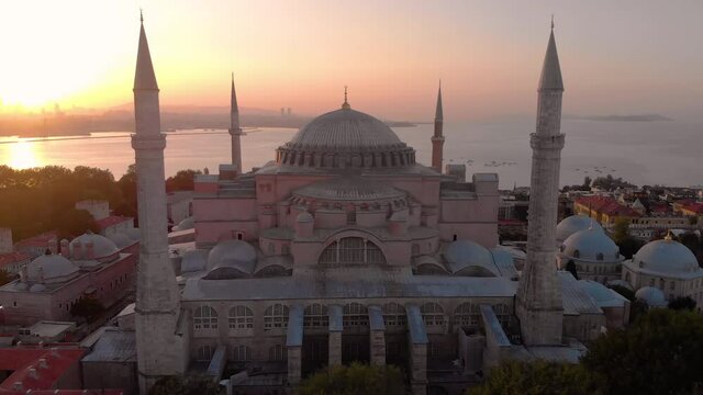 Establishing aerial drone shot of a Hagia Sophia Holy Grand Mosque (Ayasofya Camii) with Bosphorus and city skyline on the background in Fatih, Istanbul, Turkey at sunrise