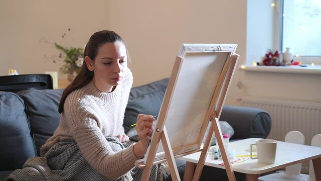 Young millennial woman painting with acrylic paints at home. Slow down hobby for lockdown