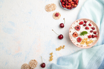 Rice flakes porridge with milk and strawberry in ceramic bowl on white concrete background. Top view, copy space.
