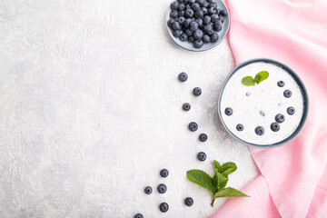 Yogurt with blueberry in ceramic bowl on gray concrete background. top view, flat lay, copy space.