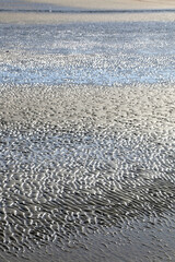 Wave pattern in the sand, illuminated by sunlight. Selective focus.