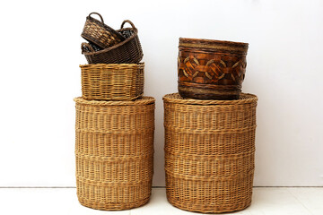 Two stacks of handmade natural wicker straw baskets for home storage of kids toys and small goods at white interior