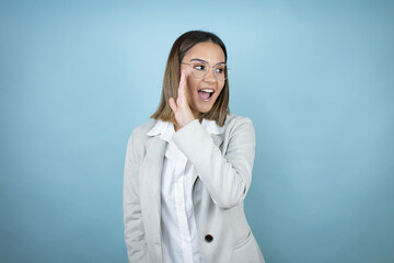 Young business woman over isolated blue background hand on mouth telling secret rumor, whispering malicious talk conversation