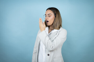 Young business woman over isolated blue background bored yawning tired covering mouth with hand. Restless and sleepiness.