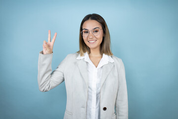 Young business woman over isolated blue background showing and pointing up with fingers number two while smiling confident and happy