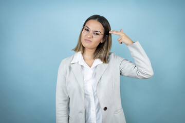 Young business woman over isolated blue background Shooting and killing oneself pointing hand and fingers to head like gun, suicide gesture.