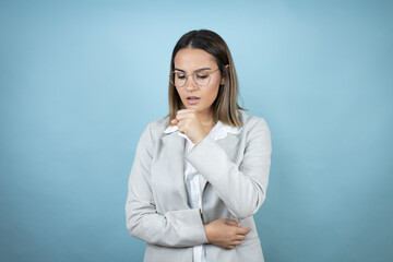 Young business woman over isolated blue background with her hand to her mouth coughing