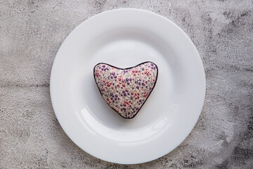 Red heart on plate on wooden background.