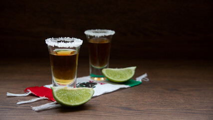 shots of Mexican tequila with salt on the rim and lemons, on a scarf of the Mexican flag with the phrase viva mexico