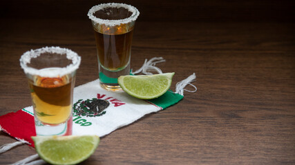shots of Mexican tequila with salt on the rim and lemons, on a scarf of the Mexican flag with the phrase viva mexico