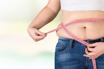 Female fat figure with measuring tape on a light background