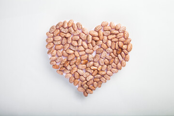 heart made of raw pinto beans on white background, healthy life and nutrition concept