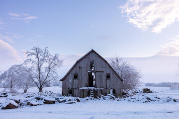 old weathered barn on snow covered midwest farm at sunrise