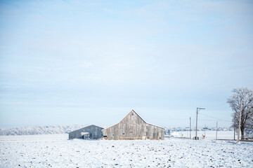 old weathered barns on snow covered midwest farm
