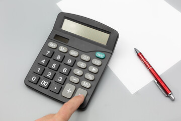 calculator on desk with grey background, pen paper