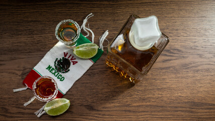 SHOTS OF TEQUILA ON VIVA MEXICO SCARF WITH LEMON AND SALT ON A RUSTIC WOODEN TABLE