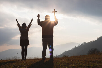 Easter Sunday concept: Silhouette man and child praying to the GOD while holding a crucifix  of Jesus Christ on autumn sunrise background