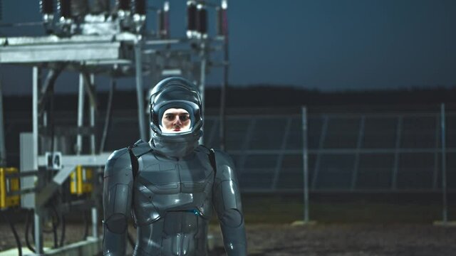 Alternative energy. Solar farm. Waist up portrait camera view of smart astronaut lifts glass in the helmet while working on ecological green station at evening. Our future and technologies concept