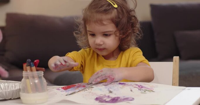 Cute little toddler girl painting. Cinematic 4K footage.