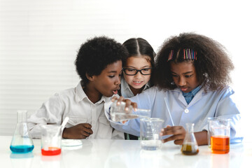 Group of teenage cute little students child learning research and doing a chemical experiment while making analyzing and mixing liquid in test tube at experiment laboratory class at school.Education