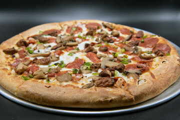 Pepperoni, sausage, mushroom, peppers, and all the works completely cover this pizza with melted cheese.