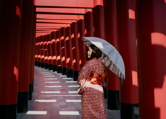 young woman in a kimono holding an umbrella walks down the aisle