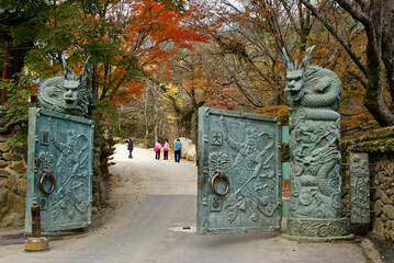 Under autumn colors, an ornate bronze gate opens into Hwaeomsa (Hwaeom-sa) Buddhist temple in South Korea's Jirisan National Park.