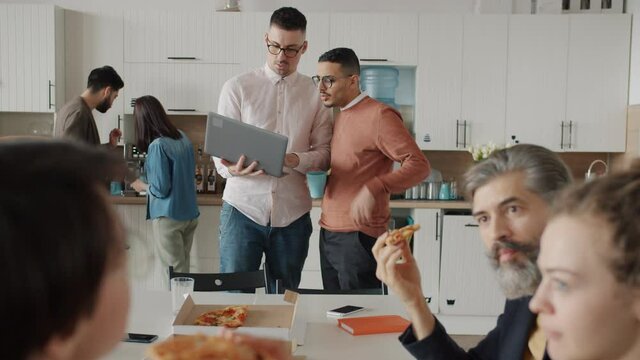 People colleagues male and female are talking eating pizza and discussing work during lunch break in office. Corporate lifestyle and communication concept.