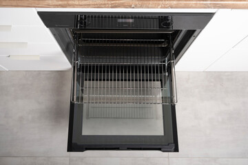 New modern electric oven built in black with screen, convention and grill, empty and open. Telescopic guides. Scandinavian loft loftstyle in a white minimalistic kitchen.