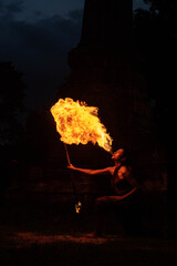 a fire artist blowing a large flame from her mouth ( a woman spits fire) in Thailand