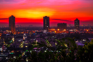 Obraz premium The high angle background of the city view with the secret light of the evening, blurring of night lights, showing the distribution of condominiums, dense homes in the capital community
