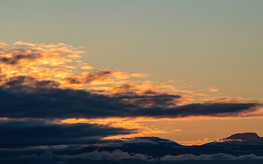 a thick layer of clouds with a glowing orange edge above the horizon near the golden hour over the coast
