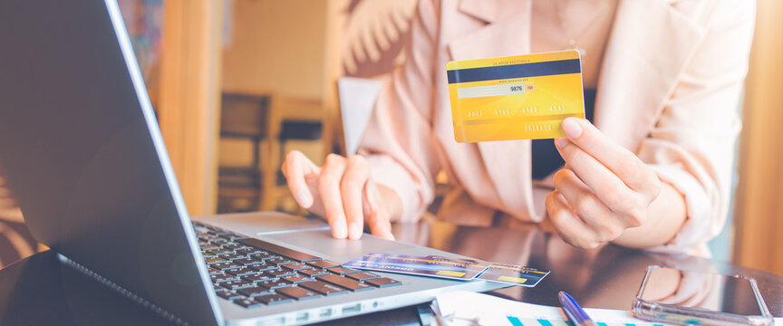 Woman holding credit card and using laptop shopping online.