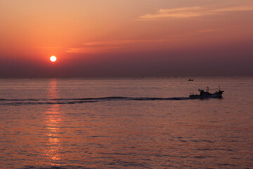 Fototapeta na wymiar Ship silhouette with sunrise on the sea