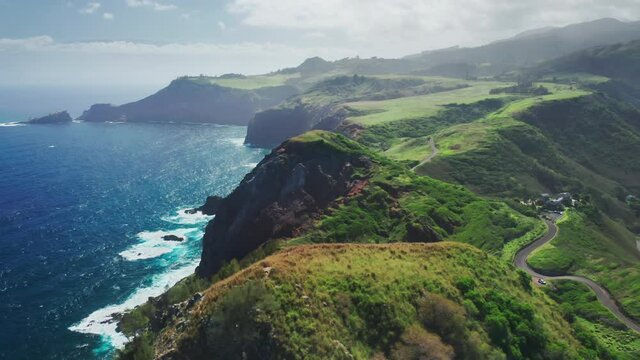Beautiful aerial panorama of road along the world famous Hawaiian coastline. Nature of green tropical island Hawaii, USA. Drone flying above scenic Maui coastline with cliffs and mountains. Travel 4K
