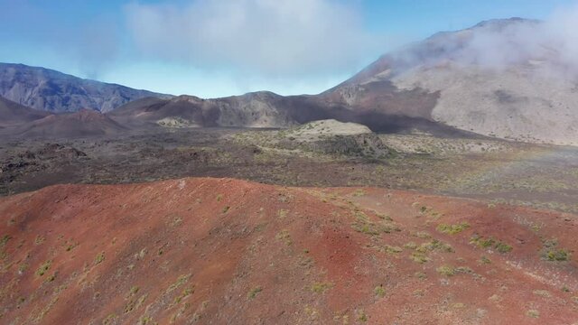 Scenic panorama of many Haleakala volcano craters with blue sky and clouds on sunny day. Trip to wilderness and outdoors adventure aerial 4K shot. Beautiful volcanic landscape of Hawaii, Maui island