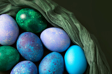 Easter eggs with drapery on a dark background. Painted village eggs in blue, green and purple close-up.