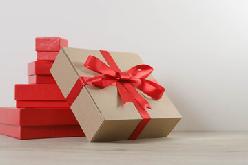 Brown gift box and red ribbon on wooden background with space