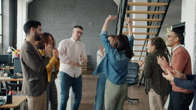 Slow motion of cheerful office workers men and women having fun dancing at corporate party enjoying music and leisure time together. People and lifestyle concept.