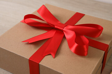 Brown gift box with red ribbon on wooden background