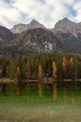 Esmerald lake and mountains in autumn with a cloudy sky and yellow trees