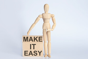 Wooden man shows with a hand text MAKE IT EASY concept on the wooden block
