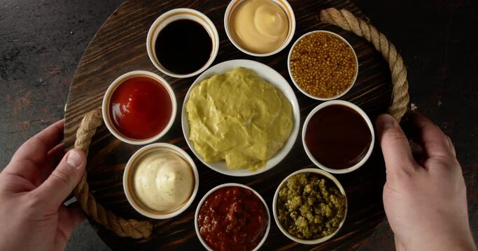 A wooden tray with different sauces is put on the table. 