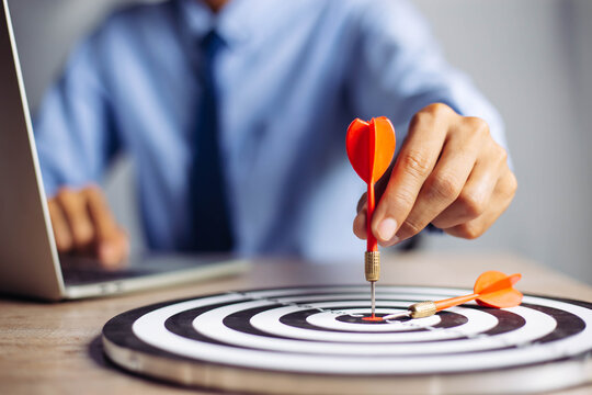 Businessman holding a darts aiming at the target center business goal concept - business targeting, aiming, focus concept,metaphor to target marketing or target arrow to business successconcept.