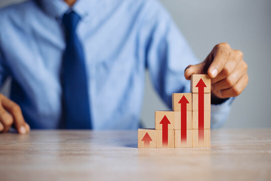 businessman hand  arranging wood block stacking as step stair with arrow up.concept for business growth success process.