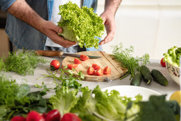 Man stands behind work surface and prepares food for healthy lunch or dinner