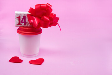 Paper coffee cups and gift box with number 14 on pink Valentine’s day background. Red heats. Coffee holiday delivery concept. Copyspace.