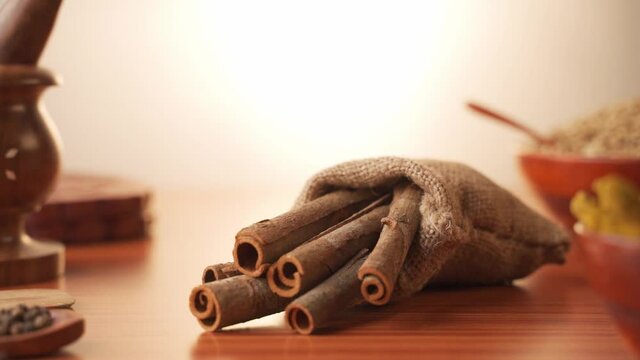 Concept of Indian masala spices showing with falling Cinnamon inside sack bag - Cinnamon which is widely used in Indian dishes.